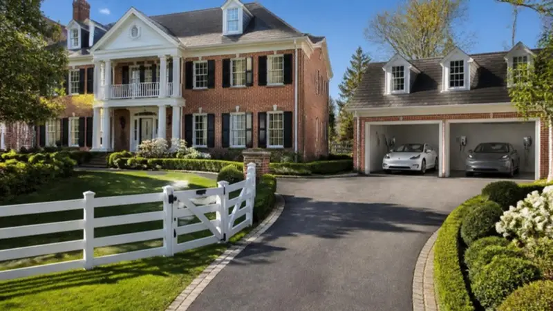 Brick colonial home with two electric cars charging in a three-car garage